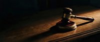 Wooden judge gavel resting on sound block atop a dark wooden table, dramatic lighting evoking justice, law, and courtroom authority.