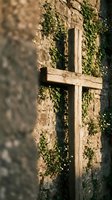 Weathered wooden cross against ancient stone wall covered with green ivy vines in warm sunlight creating peaceful spiritual atmosphere for meditation and faith.