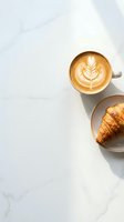 Cappuccino with latte art and fresh croissant on marble surface, overhead view for café, bakery, breakfast, and food styling projects.