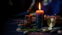 Mystical fortune telling setup with burning candle, owl figurine, compass and lavender creating atmospheric divination scene for spiritual practices.