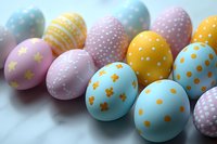 Colorful Easter eggs in pastel blue, pink, and yellow with polka dots, stars and floral patterns arranged on white marble surface. Perfect for holiday designs.