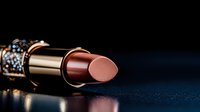 Luxurious metallic rose gold lipstick with ornate decorative cap lying on dark background with soft reflection, closeup macro shot showing texture and detail.