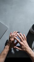 Male hands forming triangle frame gesture over laptop and coffee cup on concrete surface for creative photography composition and workspace concepts.