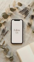 Smartphone with Follow Us text on screen, surrounded by dried lavender, eucalyptus, and thistle on linen. Flat lay social media concept.
