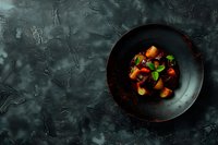 Fresh colorful vegetables and fruits in dark ceramic bowl on textured grey stone background with copy space, top view. Food photography styling.