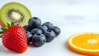 Fresh mixed fruits including strawberry, blueberries, kiwi slice and orange segment arranged on white background for healthy eating and nutrition concepts.