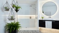 Scandinavian bathroom interior with hanging geometric planters, potted ferns, round mirror, glass shower enclosure and minimalist vanity design.