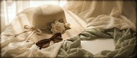 Elegant straw sun hat with white flower decoration and vintage sunglasses on soft white bedding creates romantic summer vacation mood for travel concepts.