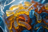 Colorful gummy worms candy in plastic packaging with vibrant orange and blue translucent sweets for confectionery and snack food concepts.