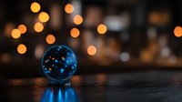 Glowing blue glass sphere with constellation pattern reflecting on dark surface against blurred warm bokeh lights creating magical atmosphere.
