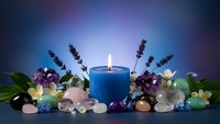 Blue candle surrounded by healing crystals, gemstones and lavender sprigs creating peaceful spa meditation atmosphere for wellness and relaxation rituals.