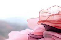 Delicate layers of translucent pink fabric create soft waves and folds against light background, showcasing ethereal texture and gentle movement in fashion design.