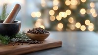 Black peppercorns in wooden bowl with mortar and pestle on rustic board against blurred holiday lights, pine branch decoration, food styling.