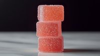 Stack of pink sugar-coated gummy candies on blurred background, showcasing sweet treats for confectionery advertising or food blog content.