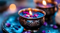 Ornate metal bowl with burning candle surrounded by purple flower petals on blue surface, creating mystical spa atmosphere with soft bokeh lighting effects.