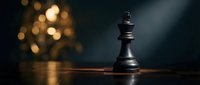 Black chess king piece standing alone on wooden board with warm bokeh lights creating dramatic atmosphere for strategy and leadership concepts.