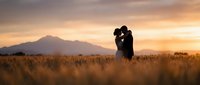 Romantic couple silhouette embracing in golden wheat field at sunset with mountain backdrop, love and connection concept for wedding photography.