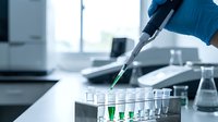 Laboratory technician using pipette to transfer green liquid samples into test tubes for scientific research and analysis in modern medical facility.