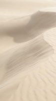 Soft beige sand dunes with flowing curves and gentle shadows creating minimalist desert landscape with warm neutral tones and organic textures.