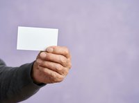 Hand holding blank white card against purple background, suitable for business cards, promotional materials, and advertising campaigns.