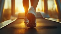 Close-up view of white sneaker sole on treadmill during sunrise workout session, with warm golden sunlight streaming through windows creating motivational atmosphere.