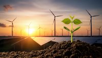 Green plant sprout growing from soil with solar panels and wind turbines at sunset representing renewable energy and sustainable development concepts.