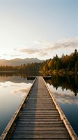 Wooden dock extending into calm lake at golden hour with coniferous forest and mountains reflected in still water, suitable for travel and nature backgrounds.
