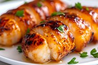Pan-seared sea scallops with caramelized golden-brown crust garnished with fresh parsley on white plate, close up view showing juicy texture and glaze.
