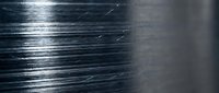 Brushed metal surface with fine linear texture and reflective highlights, suitable for industrial backgrounds, technology designs, and modern material concepts.