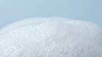 White granulated sugar crystals in macro close-up view showing texture and sparkle against soft blue background for cooking and baking concepts.