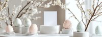 Pastel Easter eggs on white ceramic stands with spring branches and blank card mockup against neutral background, creating minimal holiday composition.