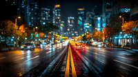 Urban night street scene with blurred city lights and wet asphalt road. Downtown traffic with colorful bokeh effects creating atmospheric cityscape for backgrounds.