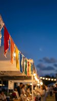 Colorful prayer flags hanging at outdoor evening market with warm lights and blue twilight sky creating festive atmosphere for celebrations and events.