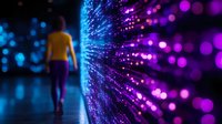 Young woman in yellow top walking along illuminated fiber optic wall with glowing blue and purple lights creating magical bokeh effect in dark space.