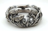 Antique silver bowl with ornate fish and floral design featuring three detailed koi carp swimming among decorative flowers and leaves, showcasing intricate metalwork craftsmanship.