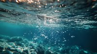 Underwater view of sunlight streaming through ocean surface with rising air bubbles and turquoise water creating magical aquatic atmosphere. Perfect for nature themes.