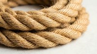 Natural jute rope coil with twisted fibers texture for nautical marine decoration crafts and rustic home design projects.