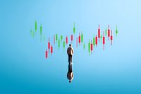 Businessman in suit standing before financial candlestick chart graph on blue background, market analysis and trading concept with reflection effect.
