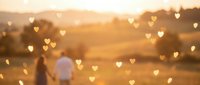 Romantic couple walking hand in hand through golden wheat field at sunset with heart-shaped bokeh lights creating magical atmosphere for love concepts.