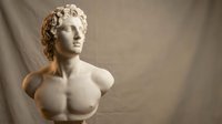 Marble bust sculpture of a young man with curly hair and classical features, displayed against neutral backdrop for art, museum, gallery, or educational use.
