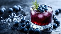 Fresh blueberry cocktail garnished with rosemary in crystal glass on dark background with scattered berries and ice. Perfect for beverage menu promotion.