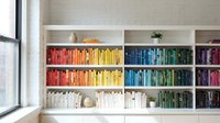 Modern home library with colorful books arranged by rainbow spectrum on white built-in shelves creating organized reading space for interior design.