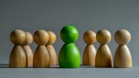 Wooden pawn figures in row with one green figure standing out from crowd, representing uniqueness, leadership and individuality concept.