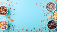 Colorful breakfast cereal and chocolate drops scattered on pastel blue background with copy space, forming decorative border frame. Food styling flatlay.