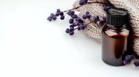 Essential oil amber glass bottle with dried lavender flowers and natural linen fabric on white background, wellness and aromatherapy concept.