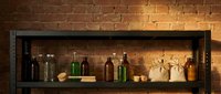 Vintage apothecary bottles and jars displayed on industrial metal shelf against warm brick wall background for rustic interior design and decoration.