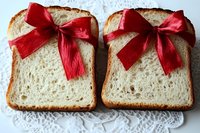 Two slices of white bread tied with red satin bows on a lace doily, presented as a festive gift for holidays and celebrations.