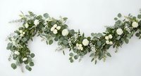 Elegant eucalyptus garland with white roses and delicate greenery for wedding decor, event styling, and romantic celebrations on white background.
