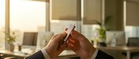 Hands of two businesspeople breaking a cigarette together in modern office environment, symbolizing commitment to quit smoking and workplace wellness.