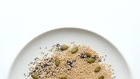 Healthy quinoa seeds with chia and pumpkin seeds arranged on white ceramic plate for nutritious meal preparation and superfood cooking.